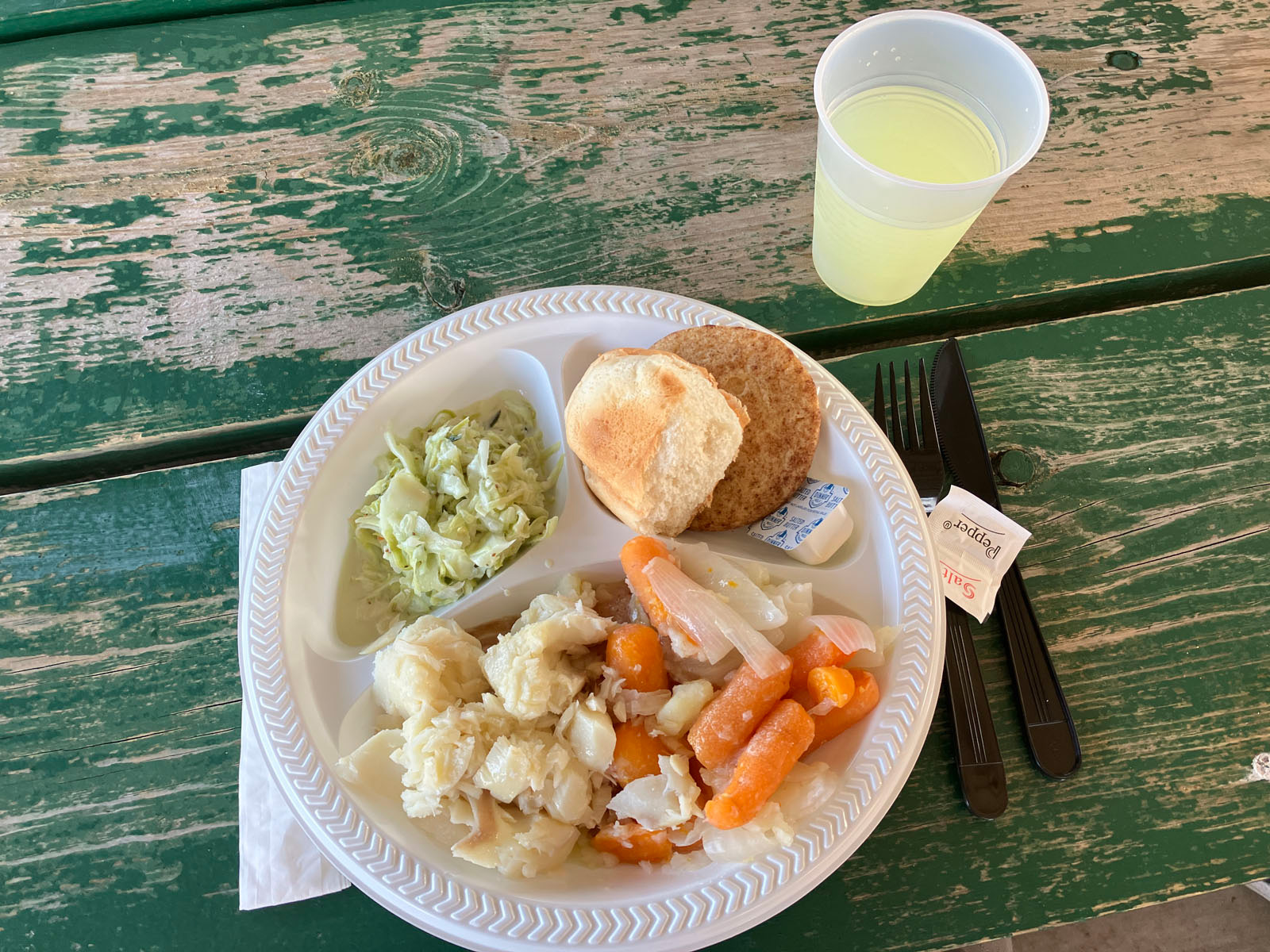 dinner plate with whitefish boil, carrots, slaw, bread, and cookie