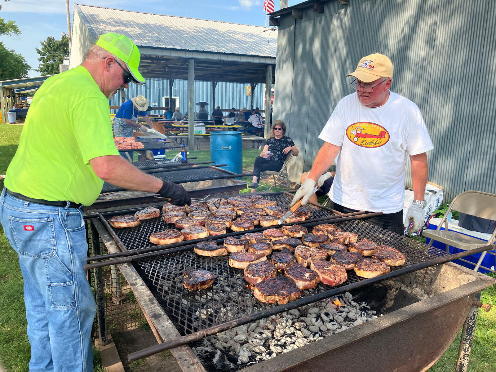 two men grilling steaks on large bbq